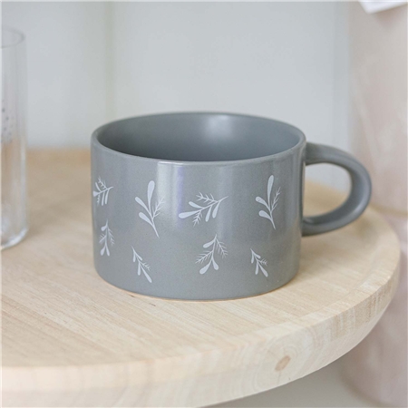 Tasse grise avec des brindilles qui tombent
